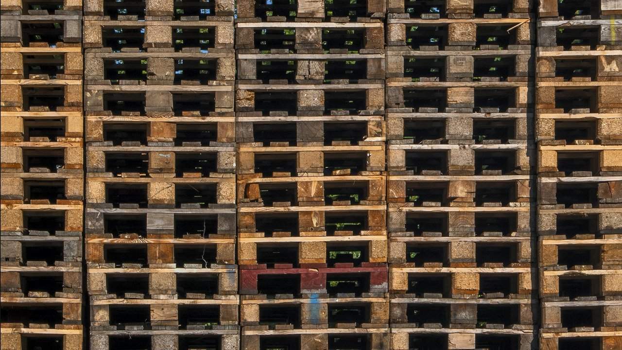 Close-up, head-on view of a tall, tightly packed wall of stacked wooden pallets