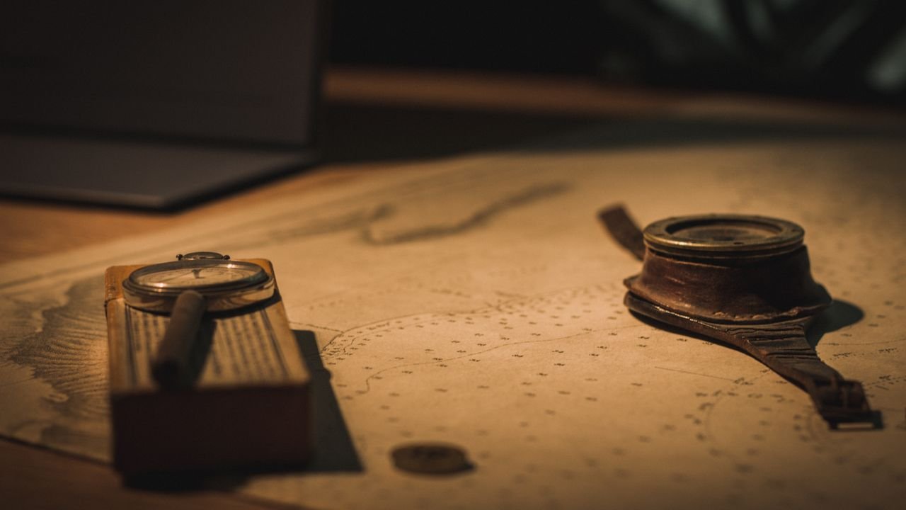 A compass and magnifying glass resting on an old nautical chart, as if tracing a strait and shipping lane, no people or logos